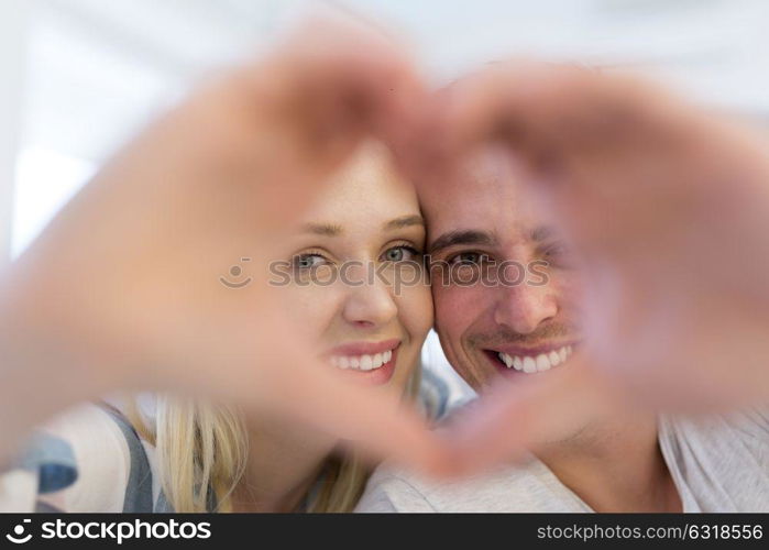 Young lovely couple making heart with hands at home