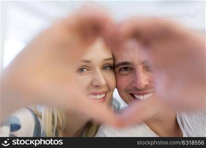 Young lovely couple making heart with hands at home