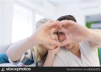 Young lovely couple making heart with hands at home