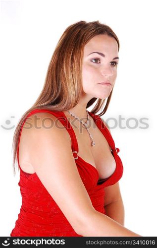 Young, lovely girl in a nice red dress and diamond necklace, looking awayfrom the camera, sitting in the studio for white background.