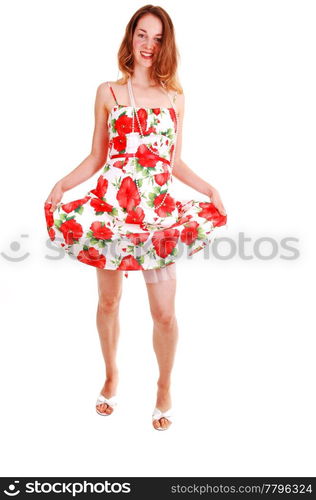 Young, lovely girl in a short colorful dress with brown hair, looking in the camera, on high heels, standing in the studio for white background.