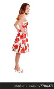 Young, lovely girl in a short colorful dress with brown hair, on high heels, standing in the studio for white background.