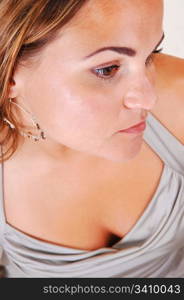 Young, lovely girl in a silver dress with nice earrings in an close-up shootof her face and chest, in the studio for white background.