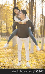 Young lovers and their pet dog playing in the woods in autumn