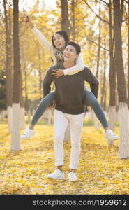 Young lovers and their pet dog playing in the woods in autumn