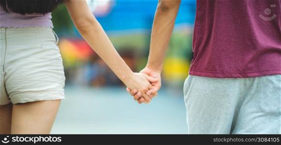 Young lovers couple hold hands, dating at amusement park, concept of happy, love, and relaxing