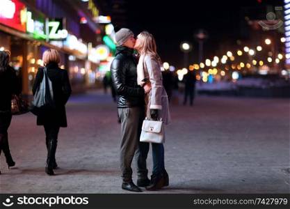 young lovers kissing on the street at night in the city, the street lights, romance