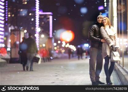 young lovers kissing on the street at night in the city, the street lights, romance