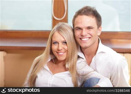 Young loving couple hugging, sitting at the window and smiling