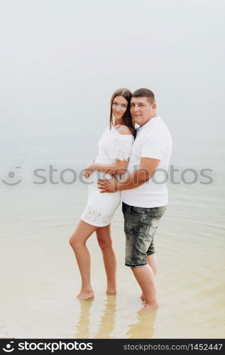 Young loving couple near the lake. A woman and a man are hugging outdoors. love story.. Young loving couple near the lake. A woman and a man are hugging outdoors. love story