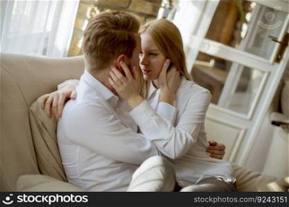 Young loving couple on the sofa sitting and hugging on sofa