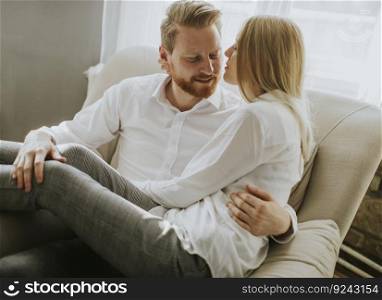 Young loving couple on the sofa sitting and hugging on sofa