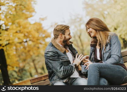 Young loving couple sitting on the bench in the autumn park