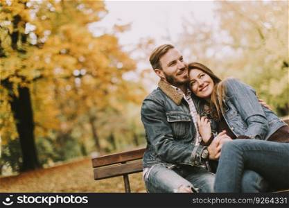 Young loving couple sitting on the bench in the autumn park