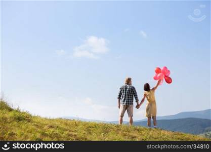 Young loving couple with balloons on sky background