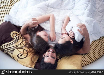 young macho playboy handsome man in bed with three beautiful sexy woman