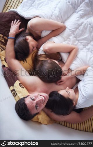young macho playboy handsome man in bed with three beautiful sexy woman