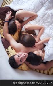 young macho playboy handsome man in bed with three beautiful sexy woman