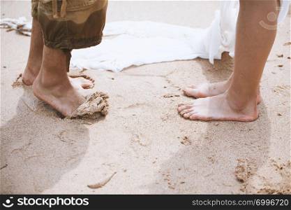 Young male and female barefoot are standing at the sandy beach