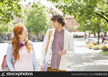 Young male and female college students talking while walking on footpath