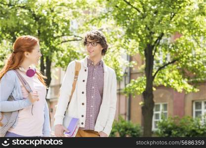 Young male and female college students talking while walking on street
