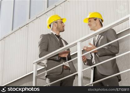 Young male architect discussing on stairway against building