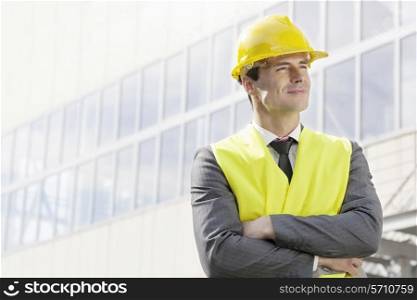 Young male architect standing arms crossed outside office building