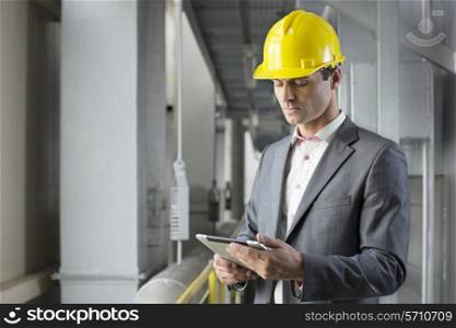 Young male architect using tablet computer in industry