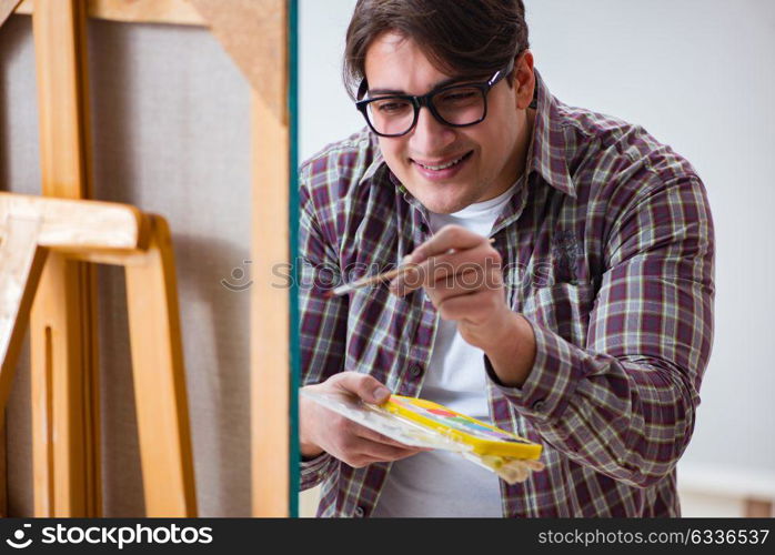 Young male artist drawing pictures in bright studio