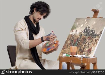 Young male artist mixing colors while painting