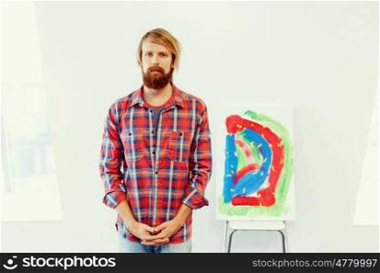 Young male artist standing with a picture. Young male artist standing with his picture