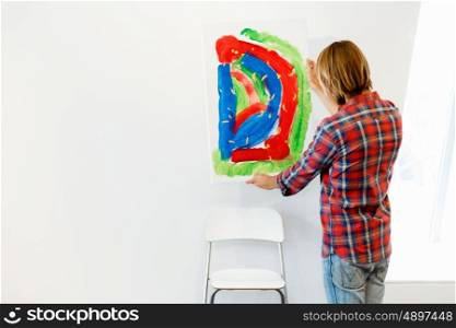 Young male artist standing with a picture. Young male artist standing with his picture