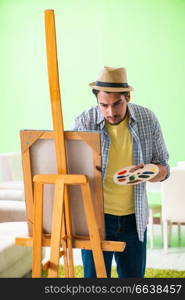 Young male artist working on new painting in his studio