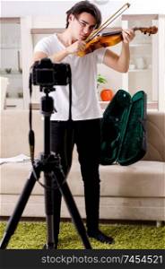 Young male blogger playing violin at home  