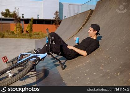 Young male bmx biker leisures on r&,teenager on training in skatepark. Extreme bicycle sport, dangerous cycle exercise, risk street riding, biking in summer park. Young male bmx biker leisures on r&in skatepark