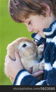 Young male boy child outside playing with his pet rabbit