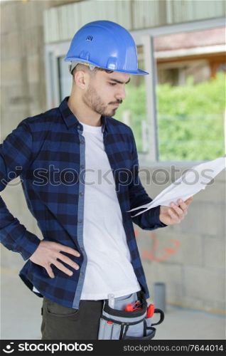 young male builder studying plans