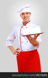 Young male chef in red apron against grey background