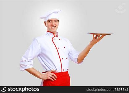 Young male chef in red apron against grey background