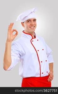 Young male chef in red apron against grey background