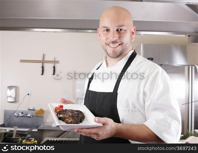young male chef presenting a juicy ribeye steak with tomatoes