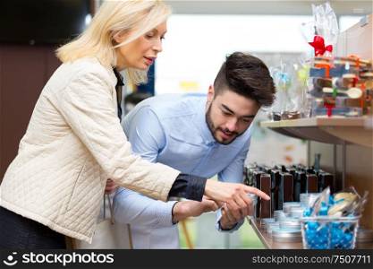 young male clerk serving mature woman in boutique