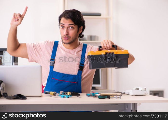 Young male contractor repairing computer  