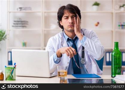Young male doctor drinking in the office 