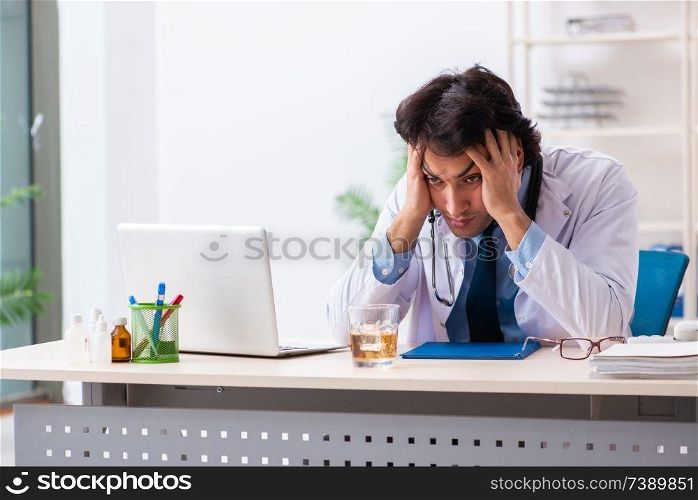 Young male doctor drinking in the office 