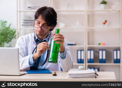 Young male doctor drinking in the office 