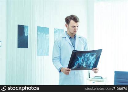 Young male doctor examining checking chest x-ray radiography film of patient at ward hospital.Medical surgery and orthopedics health care concept