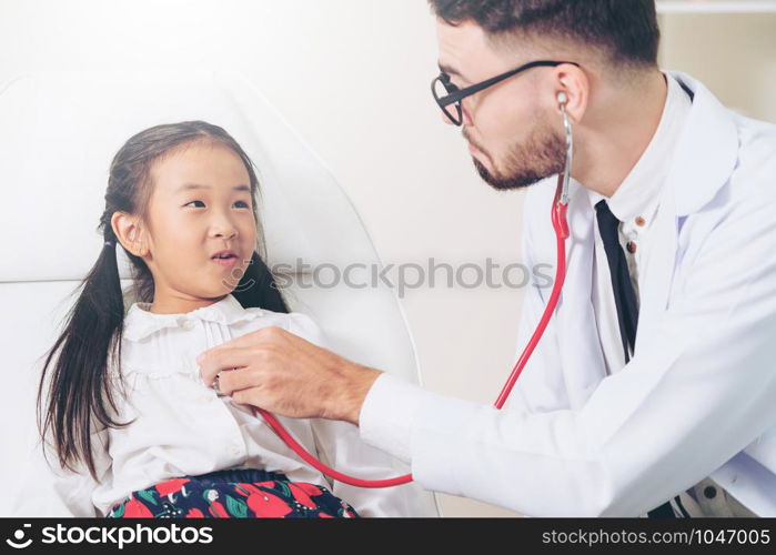 Young male doctor examining little kid in hospital office. The kid is happy and not afraid of the doctor. Medical children healthcare concept.