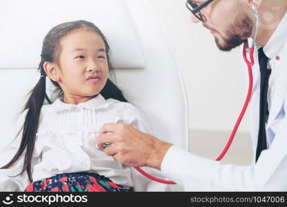 Young male doctor examining little kid in hospital office. The kid is happy and not afraid of the doctor. Medical children healthcare concept.