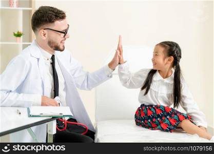 Young male doctor examining little kid in hospital office. The kid is happy and not afraid of the doctor. Medical children healthcare concept.